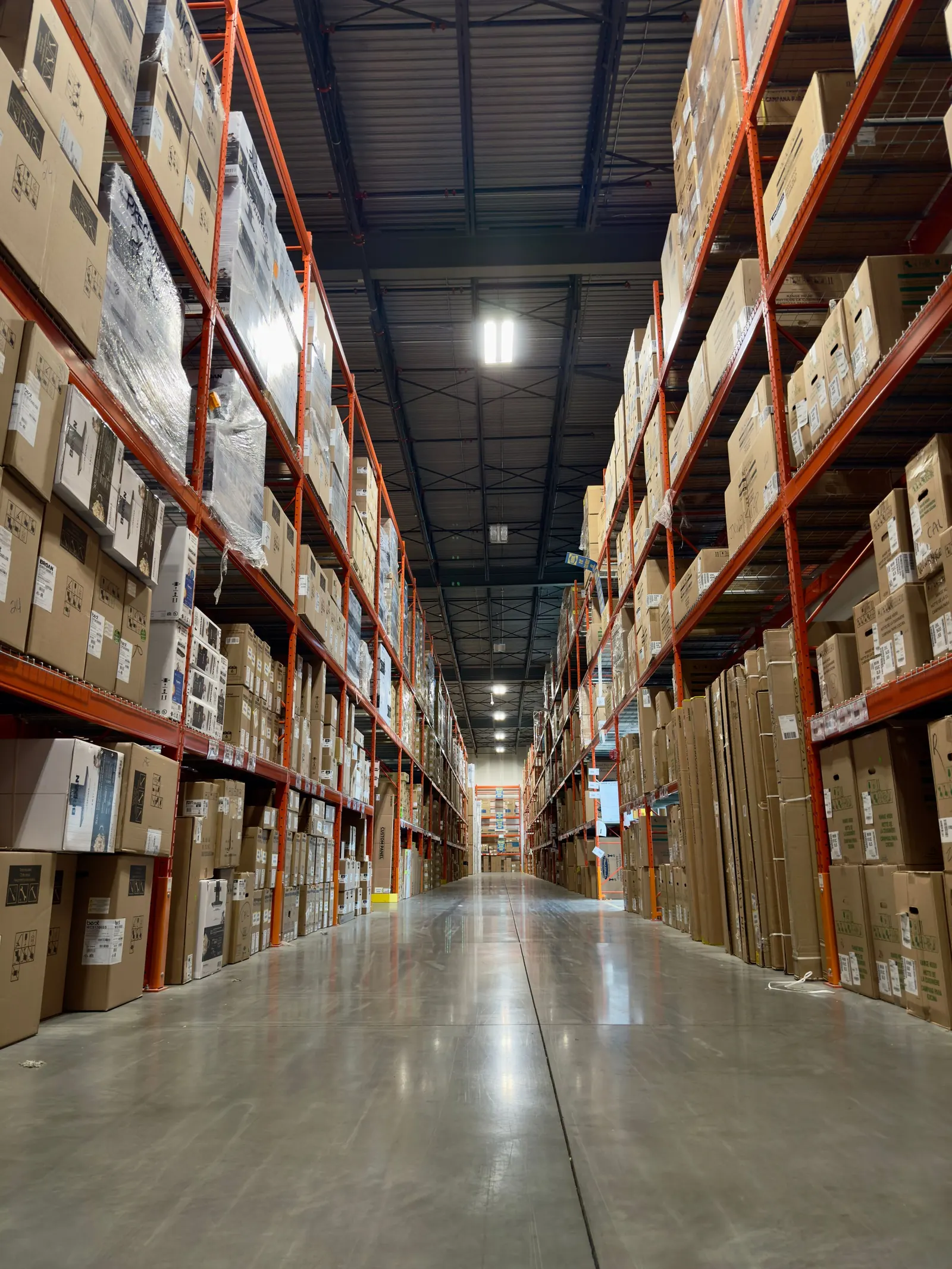 A warehouse aisle with boxed stock on tall shelves